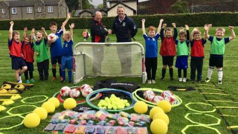 Lead teacher and a group of pupils show-off some new sports equipment on the playing field