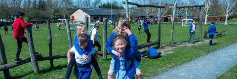 Girls playing piggyback in the school field