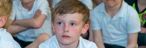 Group of boy sat on the floor listening to teacher