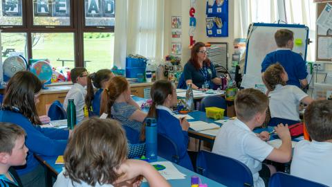 Classroom of pupils , a boy is writing on a whiteboard 