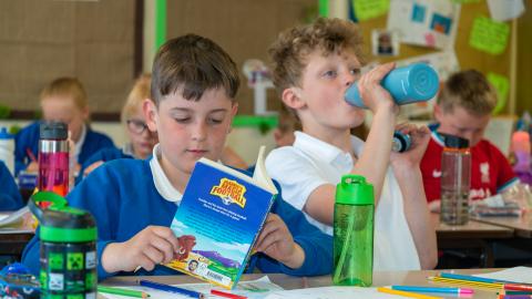 People's in the classroom boy in the foreground reading a book