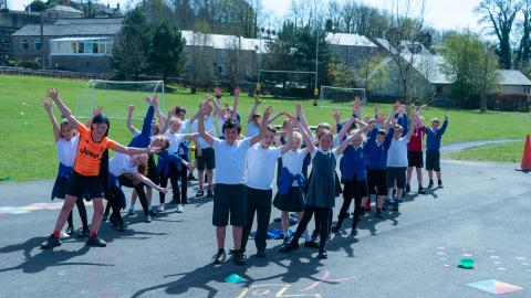 Pupils lined up in the playground with their hands in the air