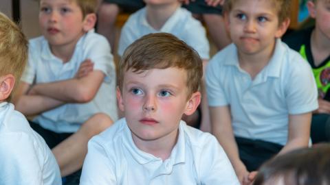 Group of boy sat on the floor listening to teacher