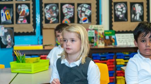 Three pupils are quietly listening to the teacher