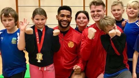 Children wearing medals standing with their instructors, kickboxing maybe